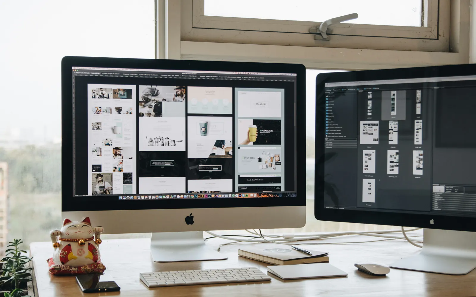 Zwei Monitore auf einem Schreibtisch zeigen Layout-Entwürfe einer Website
