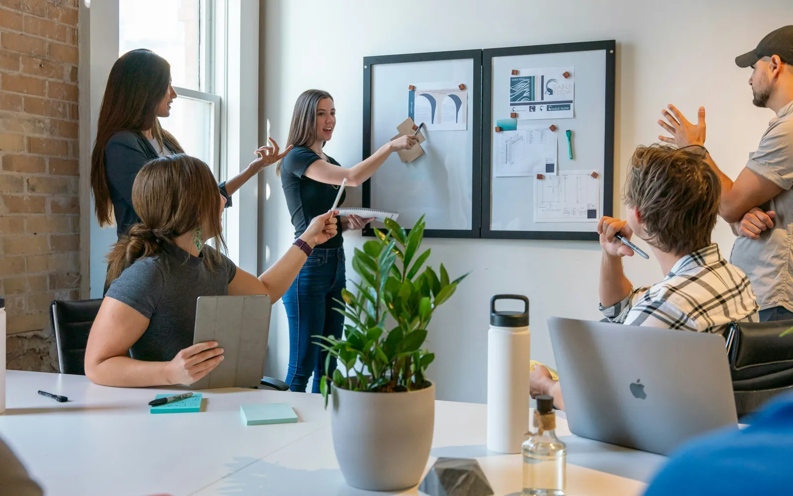 Ein Team steht vor einer Wand mit angehefteten Auswertungen und bespricht sie